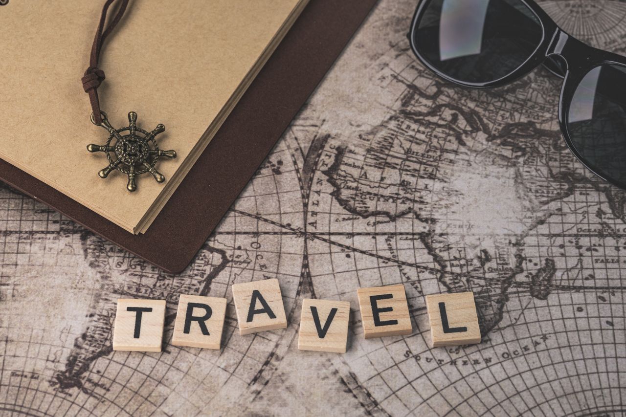 get-in-touch Close-up of travel items including map, helm pendant, notebook, and sunglasses.