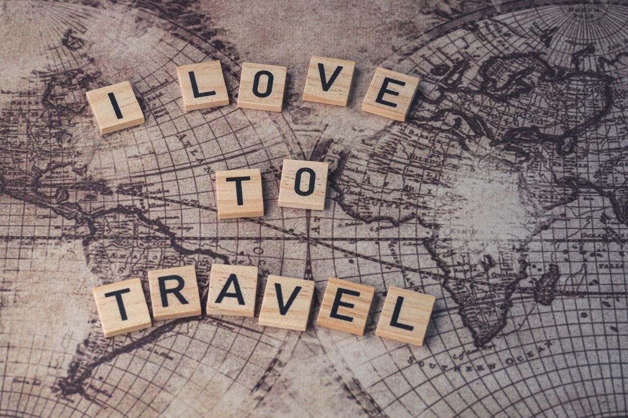 services-02 Wood scrabble tiles spelling 'I Love to Travel' on a vintage map.
