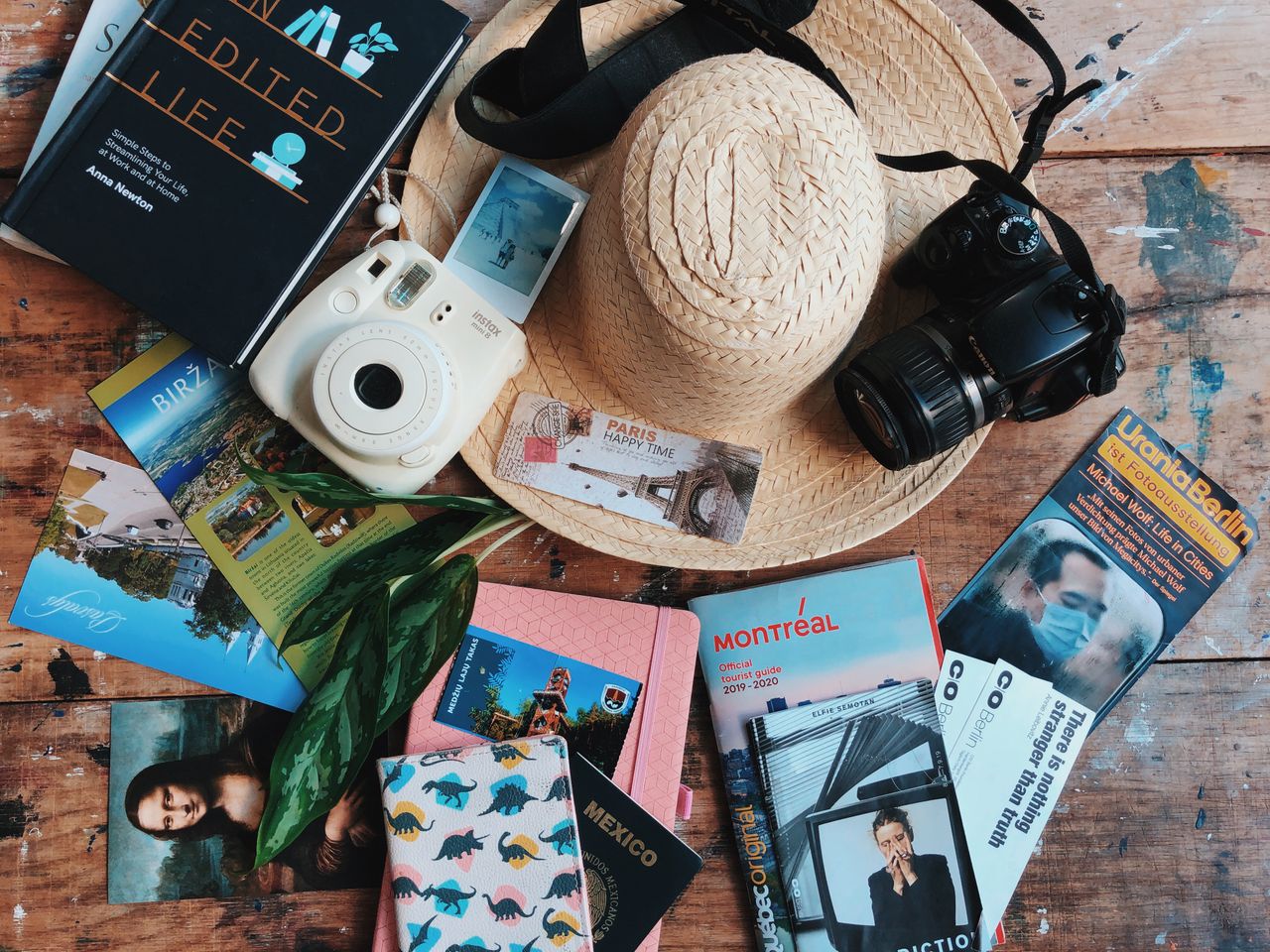services-04 Flat lay of travel accessories including a straw hat, cameras, and guidebooks on a wooden table.